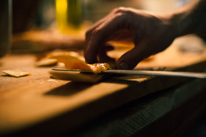 A person cutting an orange on top of a wooden table.